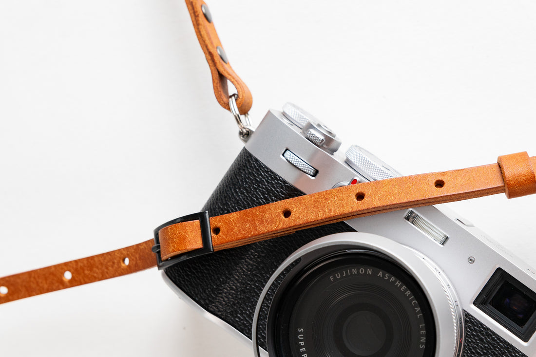 A selection of different camera straps, including leather and fabric options, laid out on a table to help photographers choose the right strap based on style, comfort, and functionality.