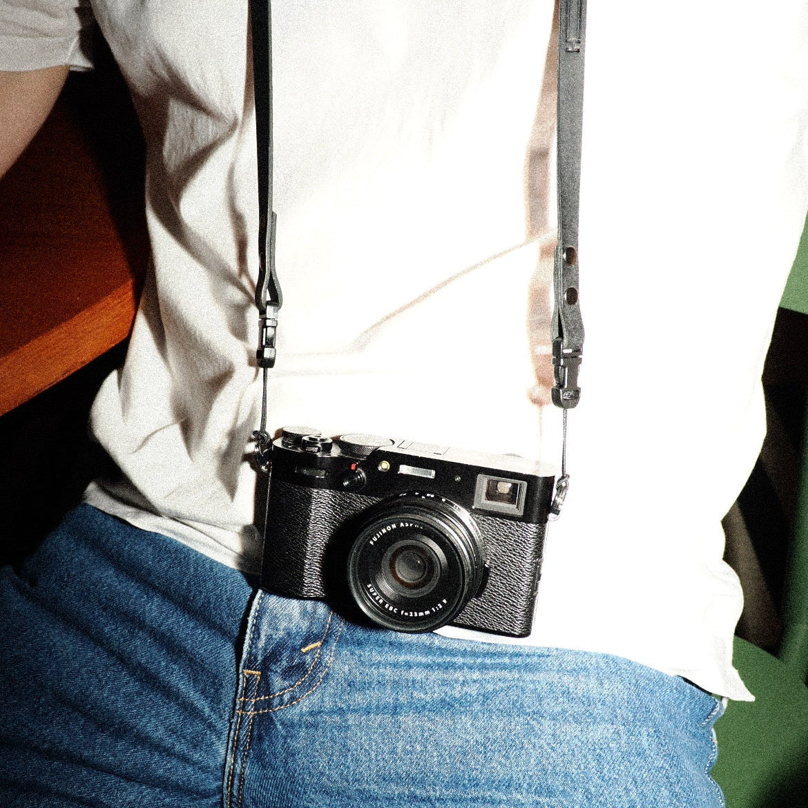 Person wearing a black camera on a strap with quick release camera strap