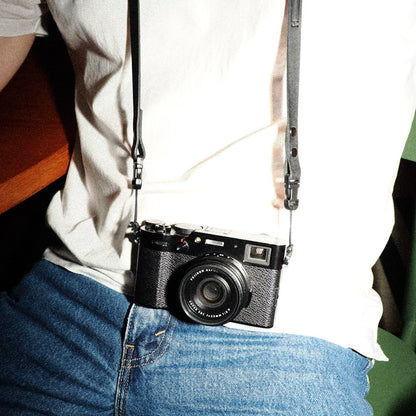 Person wearing a black camera on a strap with quick release camera strap