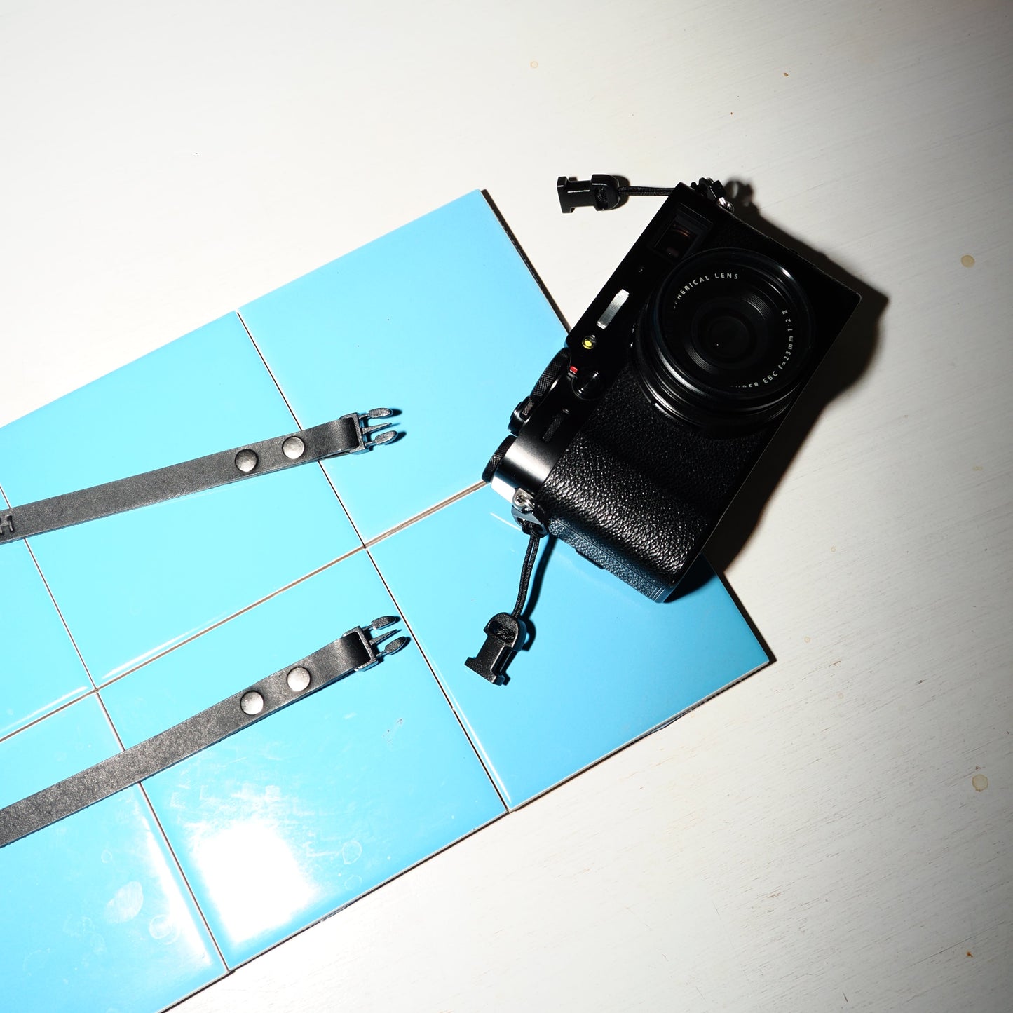 Black camera with quick release camera strap on a tiled floor
