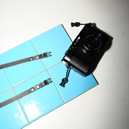 Black camera with quick release camera strap on a tiled floor