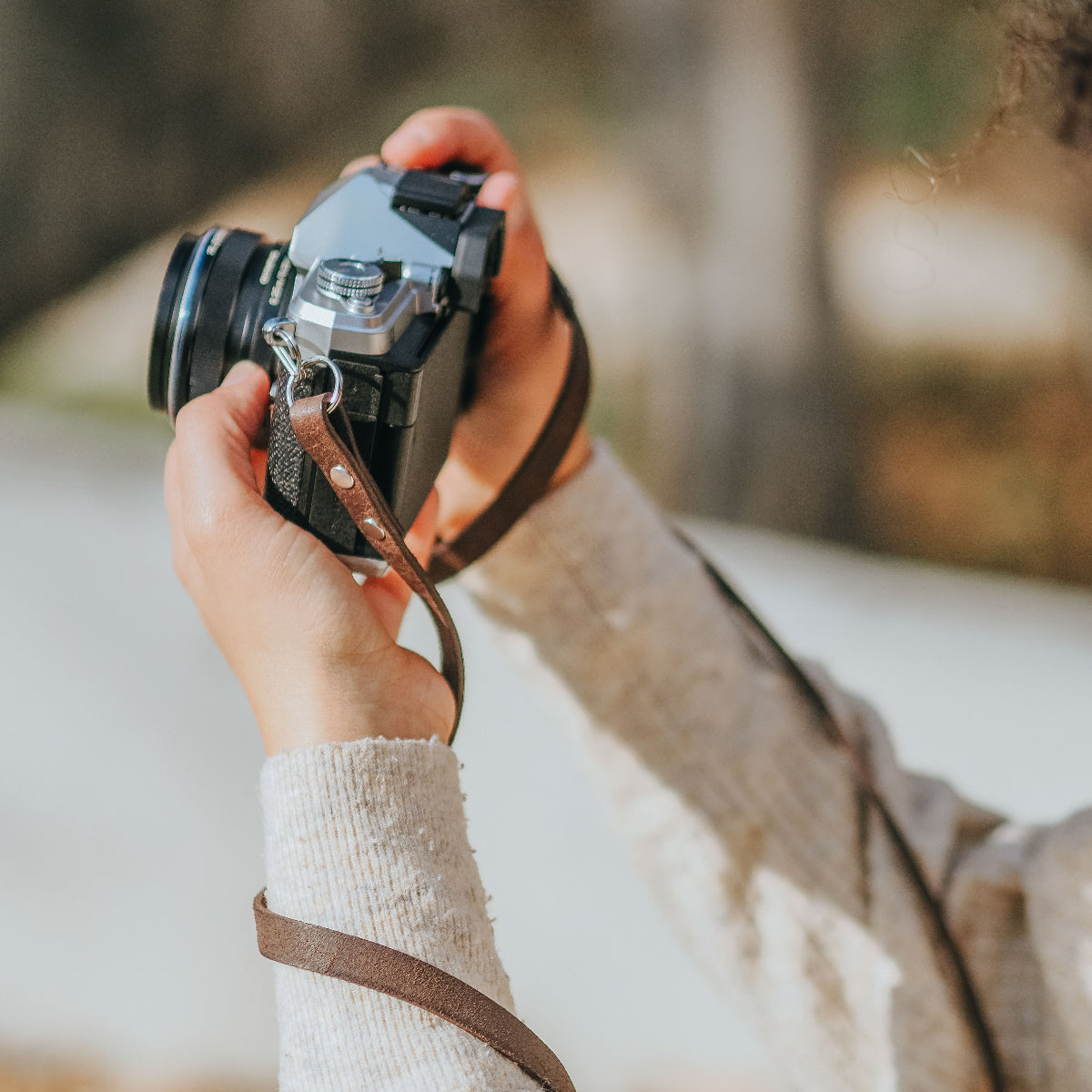 A person taking photos with the new OM SYSTEM OM-3 camera with odark brown leather camera strap from Arch Appearance